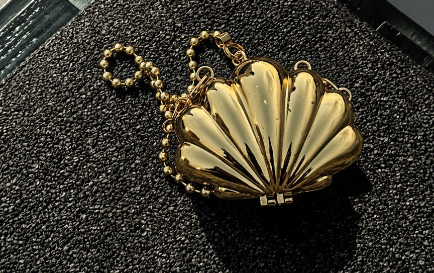 Gold shell-shaped handbag on a textured black surface like a sofa.