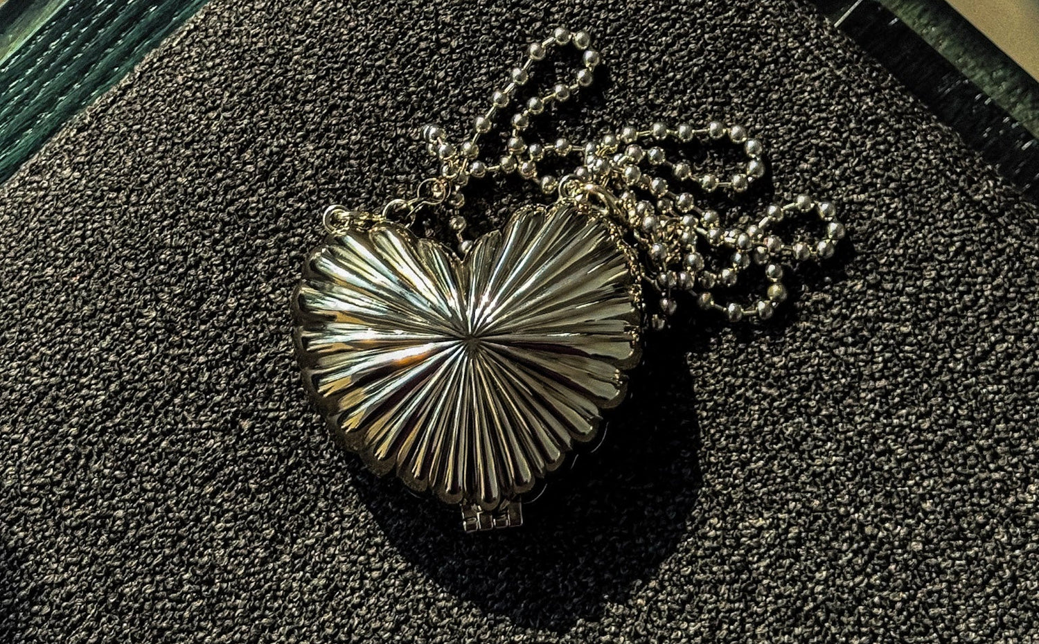 Silver heart-shaped metallic handbag in a black a textured sofa