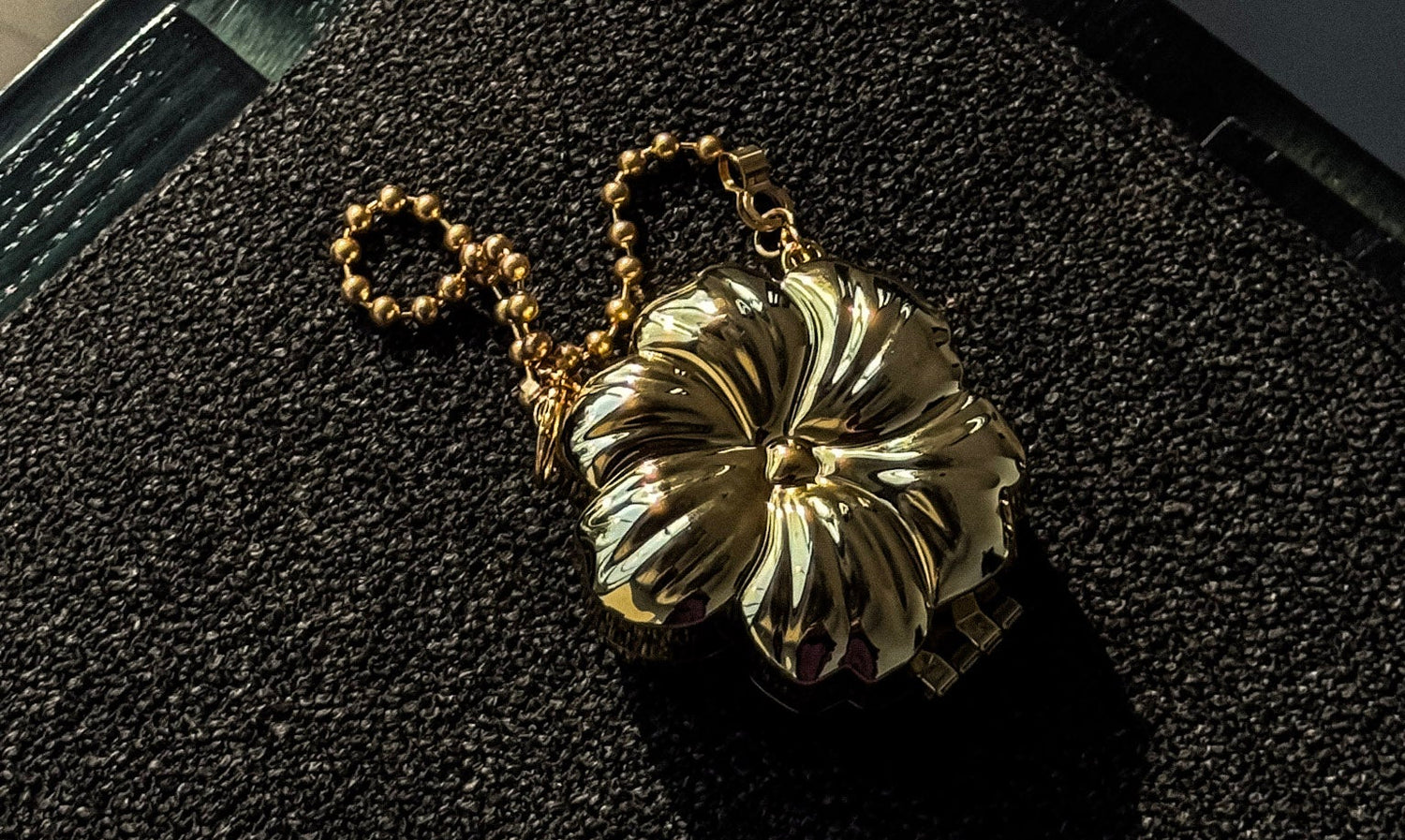 Gold floral handbag on a textured black surface, like a sofa